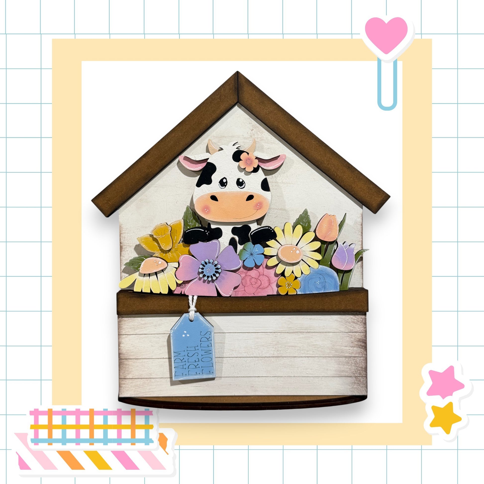 A wooden house-shaped structure with a cow decoration on it, surrounded by a variety of colorful flowers.