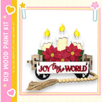 A wooden wagon decorated with poinsettia flowers and three lit candles, with the text "Joy to the World" displayed on the wagon.