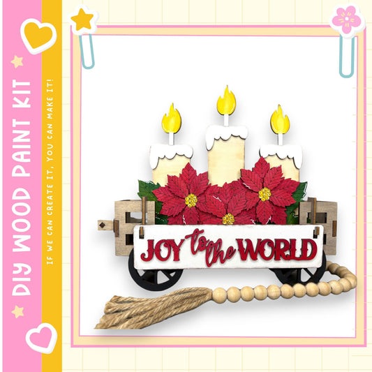 A wooden wagon decorated with poinsettia flowers and three lit candles, with the text "Joy to the World" displayed on the wagon.