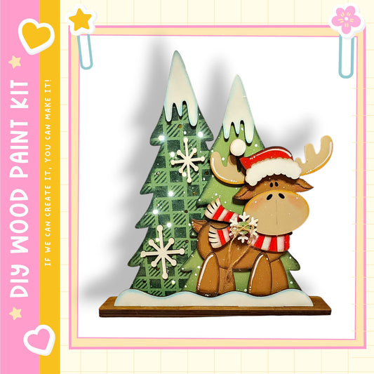 A wooden Christmas tree with a moose figure wearing a red and white hat, standing on a snowy base.