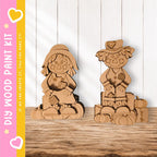 two wooden figurines, one standing and one sitting, placed on a wooden surface against a white background.