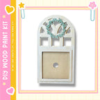 a wooden frame with a wreath hanging on it, set against a pink and yellow background with decorative elements.