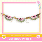 a DIY wood paint kit with a decorative border made of watermelon slices and lace. The border is displayed in a pink frame with a heart and flower motif. The text below the image encourages creativity and says, "If we can create it, you can make it!"