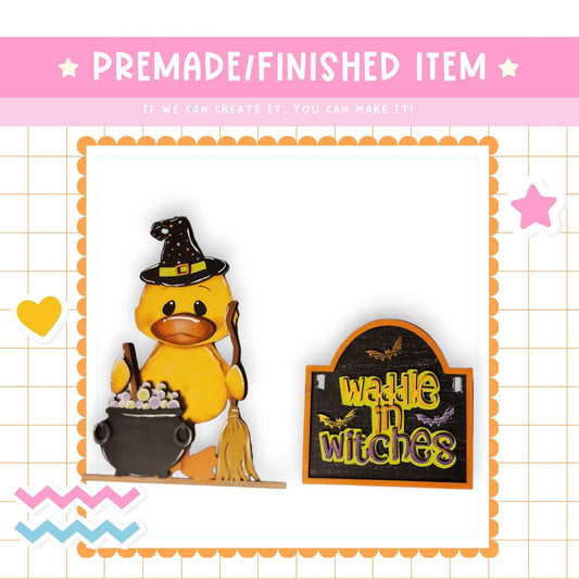 a yellow duck wearing a witch's hat and holding a cauldron, with a sign that says "waddle in witches" next to it.