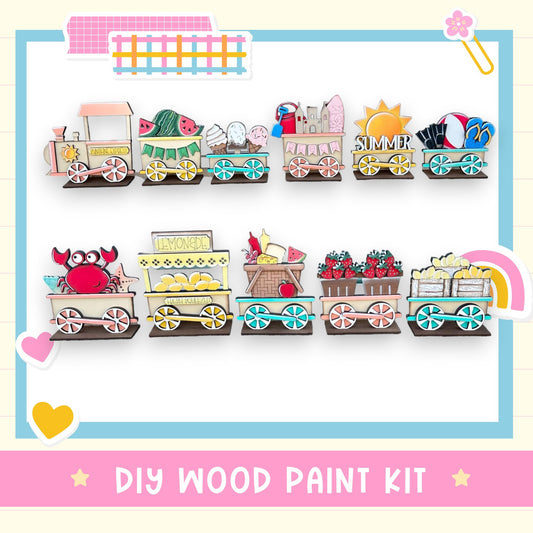 The image is a colorful and whimsical DIY wood paint kit featuring various train-themed elements, including a train with a lemonade stand, a train with a lemonade cart, and a train with a lemonade sign. The kit appears to be designed for children to create their own train sets using the provided wood paint and other materials.