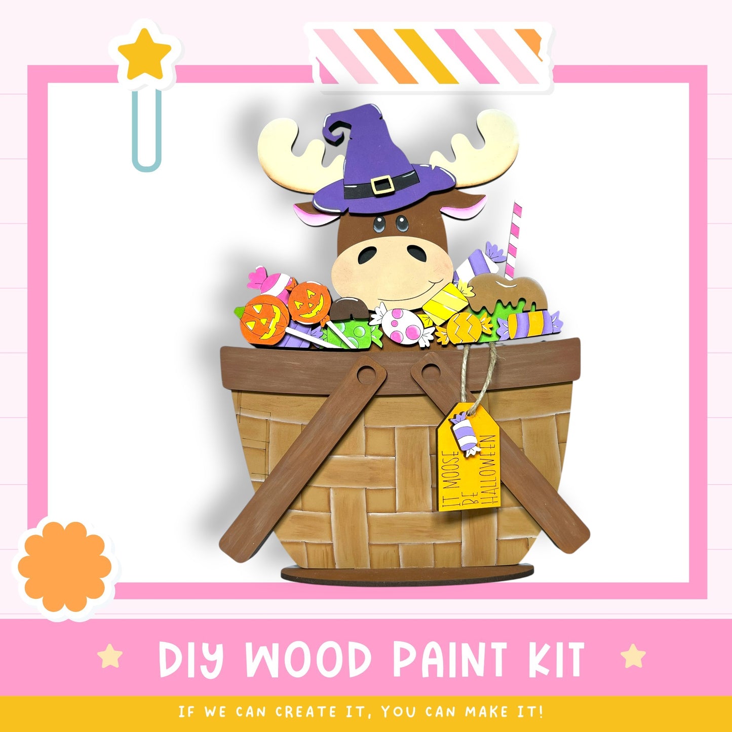 A wooden basket filled with various Halloween-themed items, including a moose wearing a witch's hat, a pumpkin, and other spooky decorations. The basket is placed on a pink background, and there is a tag attached to it. The image also includes text that says "DIY WOOD PAINT KIT" and "IF WE CAN CREATE IT, YOU CAN MAKE IT!"