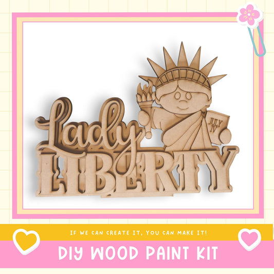 a DIY wood paint kit for creating a wooden sign or decoration with the word "LADY LIBERTY" and a wooden figure of the Statue of Liberty.