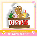 A wooden gingerbread man figure holding various baking tools, with the word "CHRISTMAS" written on a wooden sign below.