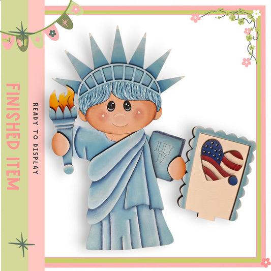 A wooden cutout of the Statue of Liberty, with a child figure holding a torch and a postcard featuring an American flag.