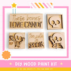 The image is a DIY wood paint kit featuring various wooden cutouts in the shape of bones, including a skeleton, a skull, and a bone. The kit appears to be designed for creating custom wooden decorations or art pieces.