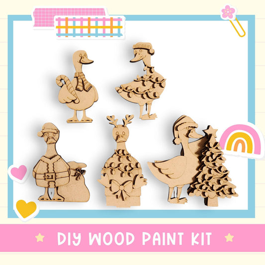 The image is a DIY wood paint kit featuring various wooden animal figurines, including ducks, reindeer, and a Christmas tree, along with a pink and blue border.