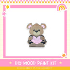 A wooden teddy bear holding a heart-shaped sign with the message "I love you" written on it.