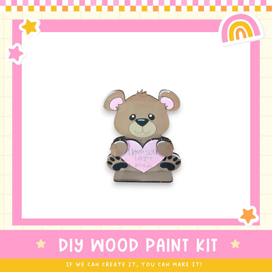 A wooden teddy bear holding a heart-shaped sign with the message "I love you" written on it.