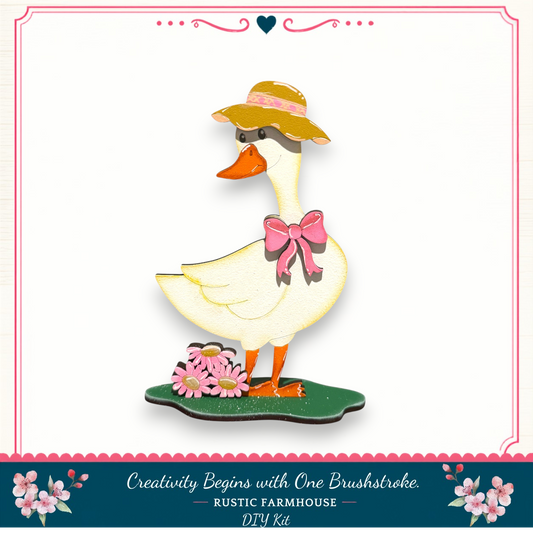 A wooden duck wearing a hat and bow, standing on a green platform with flowers, against a white background.