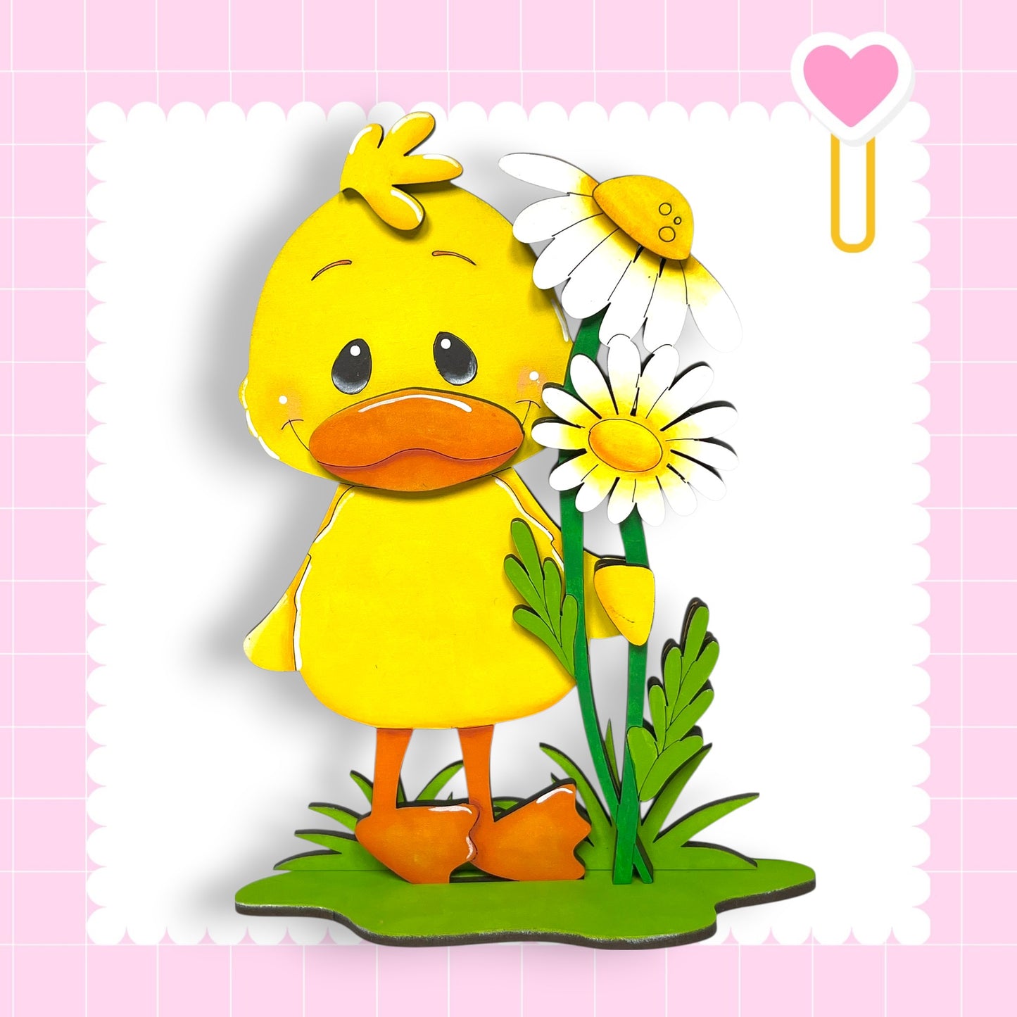 A yellow duck standing on a green surface, with a flower nearby.