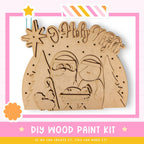 The image is a DIY wood paint kit for creating a wooden nativity scene. It features a wooden nativity scene with Santa Claus, Mary, and baby Jesus, along with decorative elements such as a star and a banner that says "HOLY NIGHT".