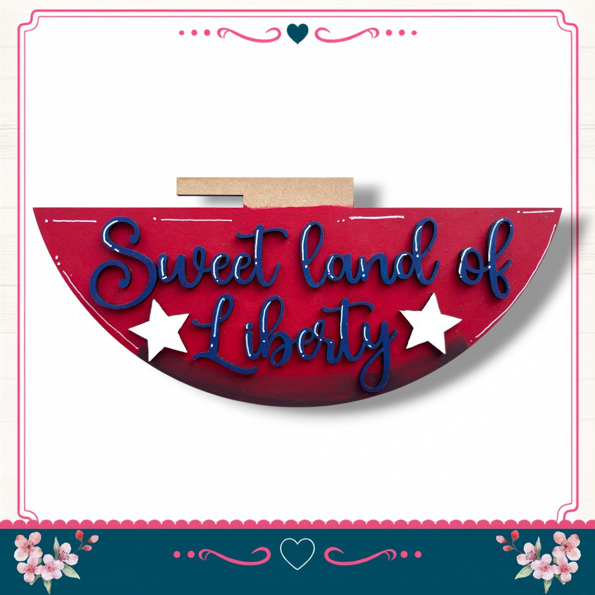 a red sign with the text "Sweet land of Liberty" written on it, surrounded by a decorative border with pink and blue floral elements.