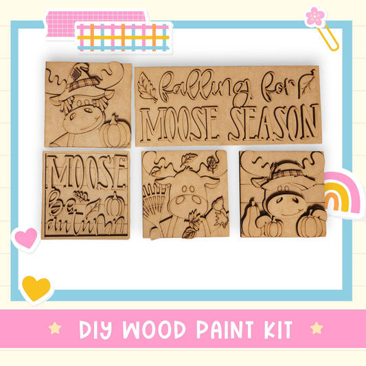 The image is a DIY wood paint kit featuring a collection of wooden cutouts with various designs, including moose and autumn-themed elements.