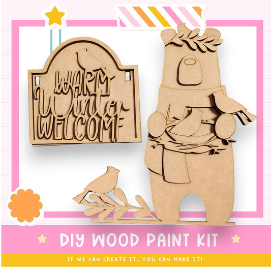 a DIY wood paint kit for creating a wooden bear and bird sign. The kit includes a wooden bear and bird figure, as well as instructions for painting the bear and bird.