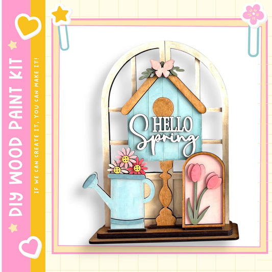 A wooden birdhouse with a painted blue roof, flowers, and the text "Hello Spring" is displayed in the image.