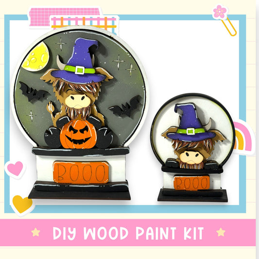 a DIY wood paint kit for creating a Halloween-themed snow globe. The kit includes a pumpkin and a witch hat, along with other Halloween-related elements.