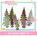a DIY wood paint kit for creating wooden trees, with a variety of colorful and patterned tree cutouts arranged in a row.