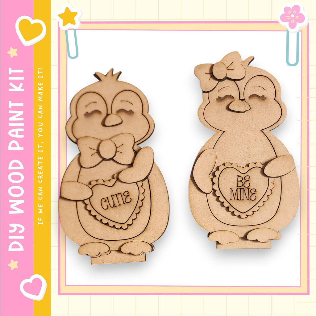 two wooden cutouts of cute penguins, each holding a heart-shaped sign with a Valentine's Day message.