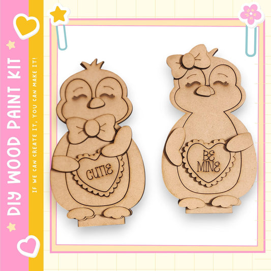 two wooden cutouts of cute penguins, each holding a heart-shaped sign with a Valentine's Day message.