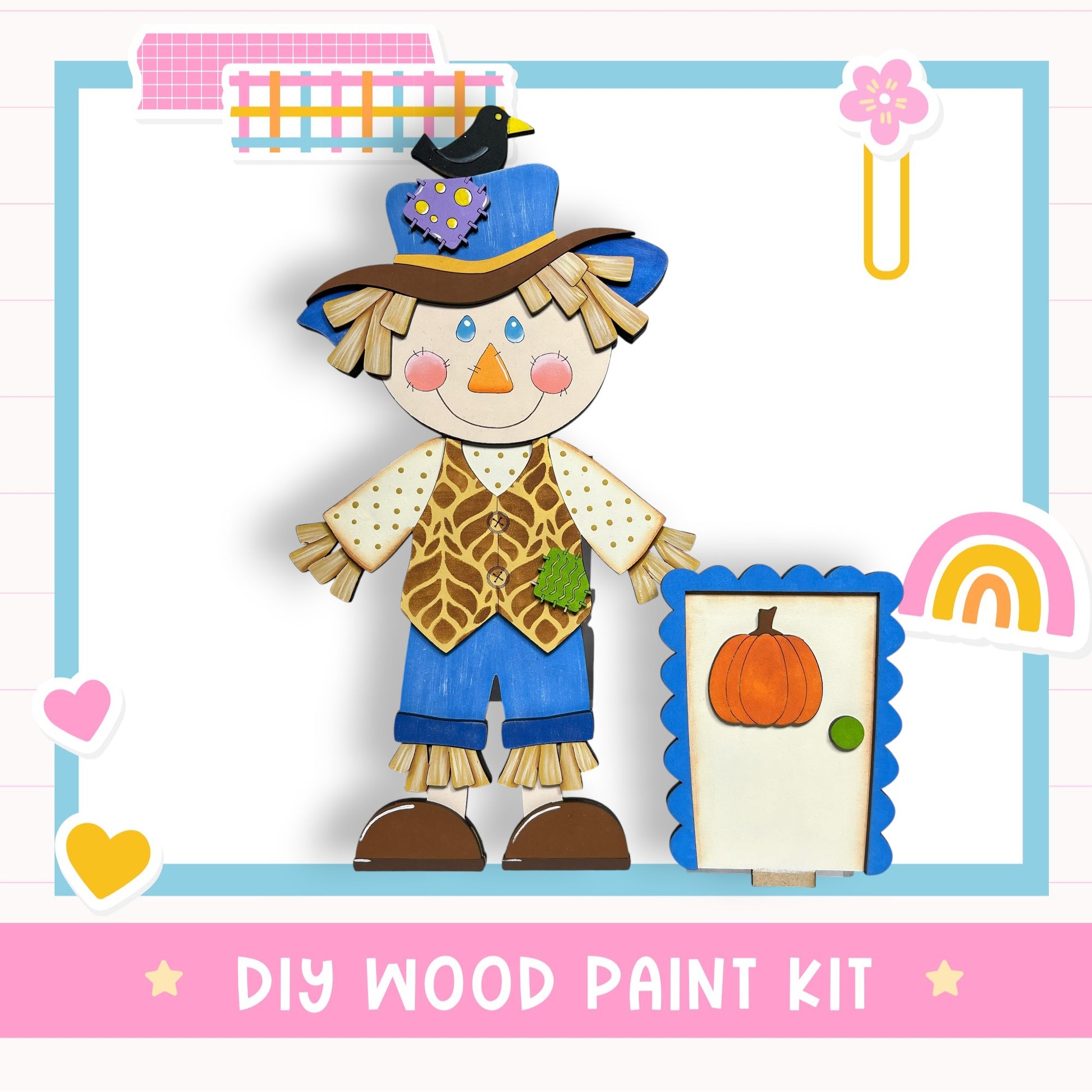 A DIY wood paint kit featuring a wooden scarecrow figure with a hat, vest, and straw hat, holding a carved pumpkin and a rainbow-colored frame.