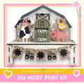 The image is a DIY wood paint kit featuring a farm scene with a barn, cow, pig, and tractor. The barn has a sign that says "FARM SWEET FARM". The barn is surrounded by a fence, and there are banners hanging from it. The barn is the central focus of the image, with the farm scene surrounding it.