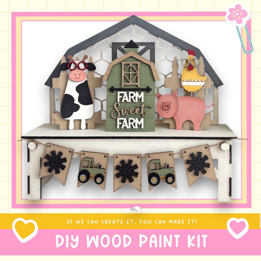 The image is a DIY wood paint kit featuring a farm scene with a barn, cow, pig, and tractor. The barn has a sign that says "FARM SWEET FARM". The barn is surrounded by a fence, and there are banners hanging from it. The barn is the central focus of the image, with the farm scene surrounding it.