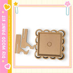 a DIY wood paint kit, including a wooden frame and a wooden piece, all set against a pink and yellow background with decorative elements.