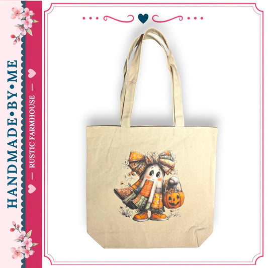 A beige tote bag with a Halloween-themed design, featuring a ghost character holding a pumpkin and a bow.