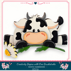 A wooden cow figurine with a flower in its mouth, sitting on a green leaf.