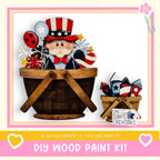 a DIY wood paint kit for creating a patriotic-themed decoration, including a wooden basket filled with patriotic-themed objects such as stars, flowers, and fireworks.