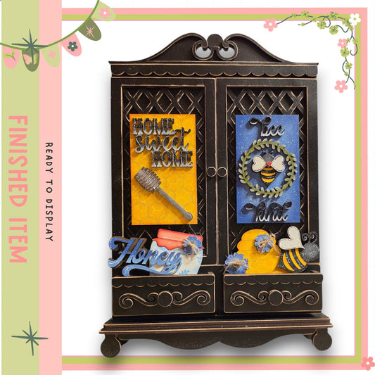 The image is a decorative wooden cabinet with various items on its surface, including a honeycomb, a bee, and other floral and honey-related elements.