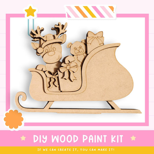 A DIY wood paint kit for creating a wooden reindeer and teddy bear on a sled, with a pink and white striped border and a star decoration.