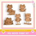 a DIY wood paint kit with five wooden frog figures in various poses, including one sitting on a castle, one holding a book, one holding a stick, one holding a stick and a book, and one holding a stick and a book.