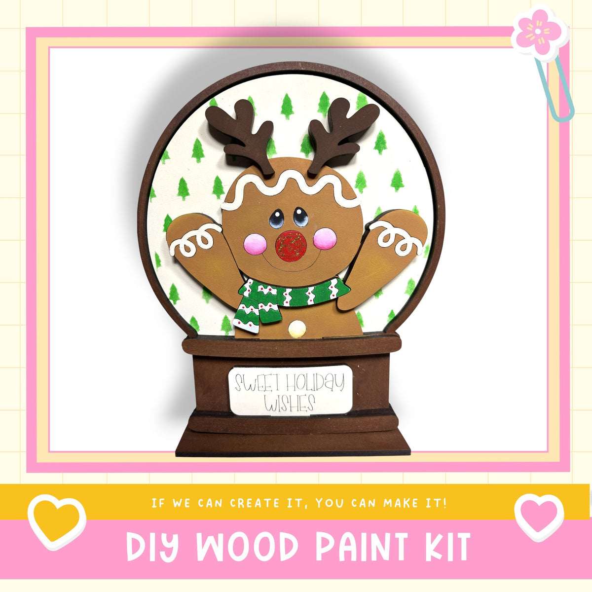 A DIY wood paint kit for creating a wooden snow globe with a gingerbread man figure, set against a pink and white background.