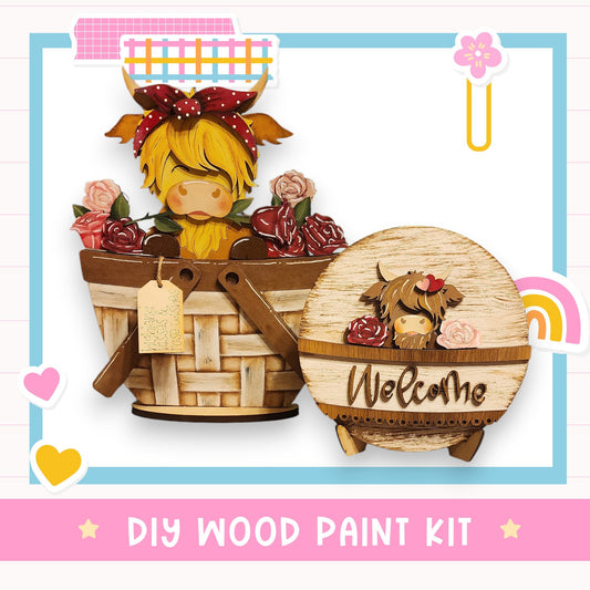 a DIY wood paint kit with a wooden basket and a wooden sign. The basket contains a wooden cow and a wooden flower, while the sign has a wooden cow and a wooden flower. The kit is presented in a pink and blue frame, and the text "DIY WOOD PAINT KIT" is displayed at the bottom.