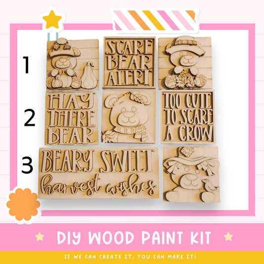 The image is a DIY wood paint kit featuring various wooden shapes and designs, including a bear, a scarecrow, and a bird.