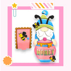 A colorful and whimsical image featuring a gnome-like character with a bee-like appearance, wearing a hat and holding a honey pot. The character is surrounded by various decorative elements, including a star, a flower, and a honey pot.