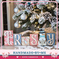 A handmade wooden sign with the word "FROSBY" made of wooden blocks, placed in front of a decorated Christmas tree with ornaments and lights.