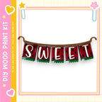 a banner with the word "SWEET" written on it, hanging from a hook. The banner is decorated with watermelon slices and green leaves, giving it a playful and summery appearance.