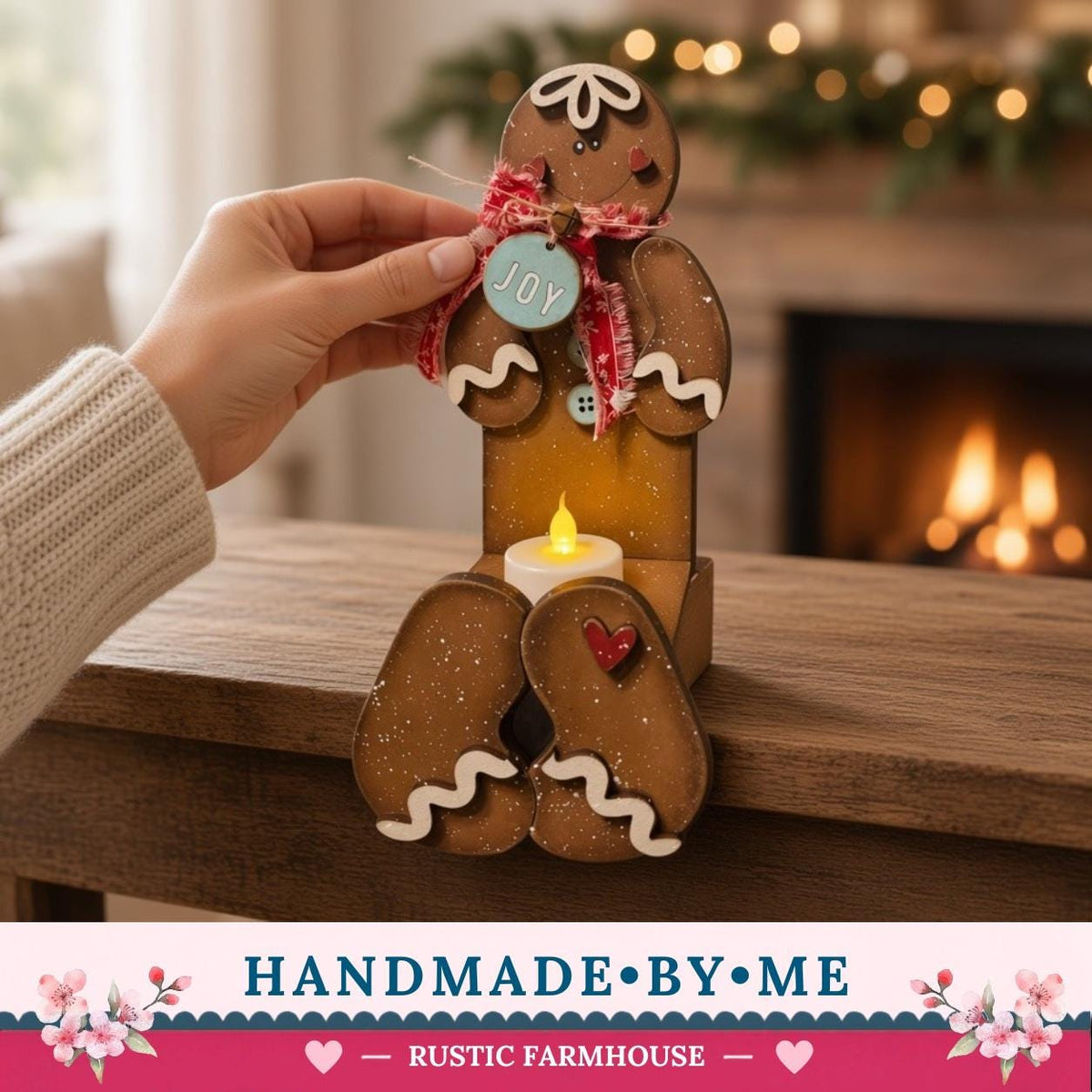 A hand is holding a gingerbread man figure with a candle in its lap, placed on a wooden surface.