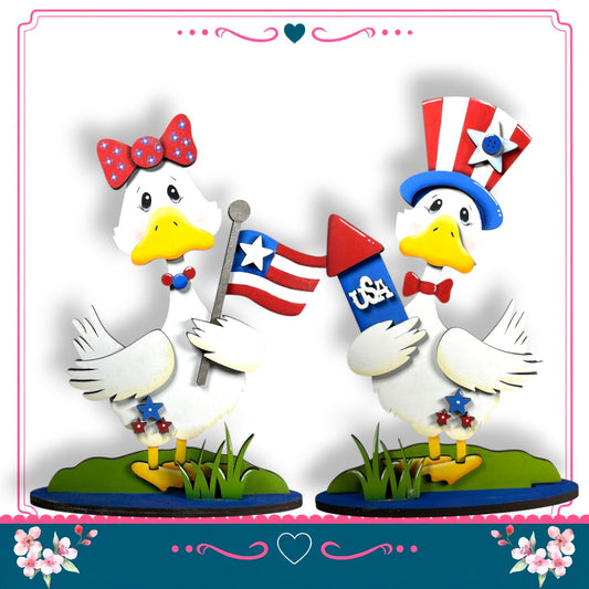 two cartoon ducks holding American flags and a firework, standing on a grassy surface.