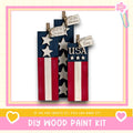 a DIY wood paint kit for creating American flags out of wooden planks. The kit includes instructions and materials for making the flags, and the image includes a heart and a flower, suggesting a creative and fun project.