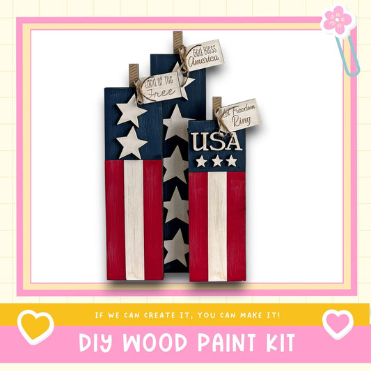 a DIY wood paint kit for creating American flags out of wooden planks. The kit includes instructions and materials for making the flags, and the image includes a heart and a flower, suggesting a creative and fun project.