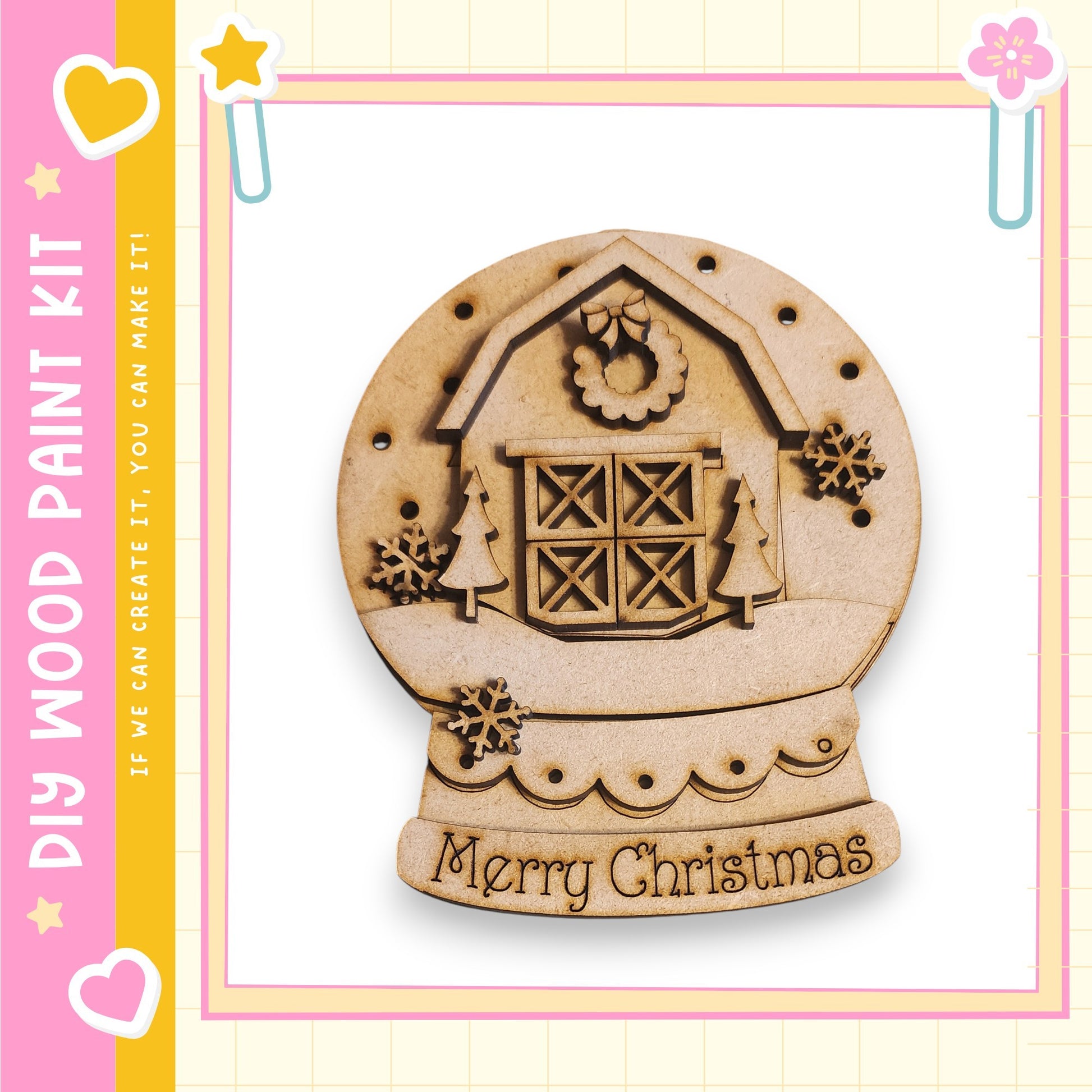 A wooden snow globe with a house and Christmas decorations, including a wreath and snowflakes, is displayed against a pink and yellow background.