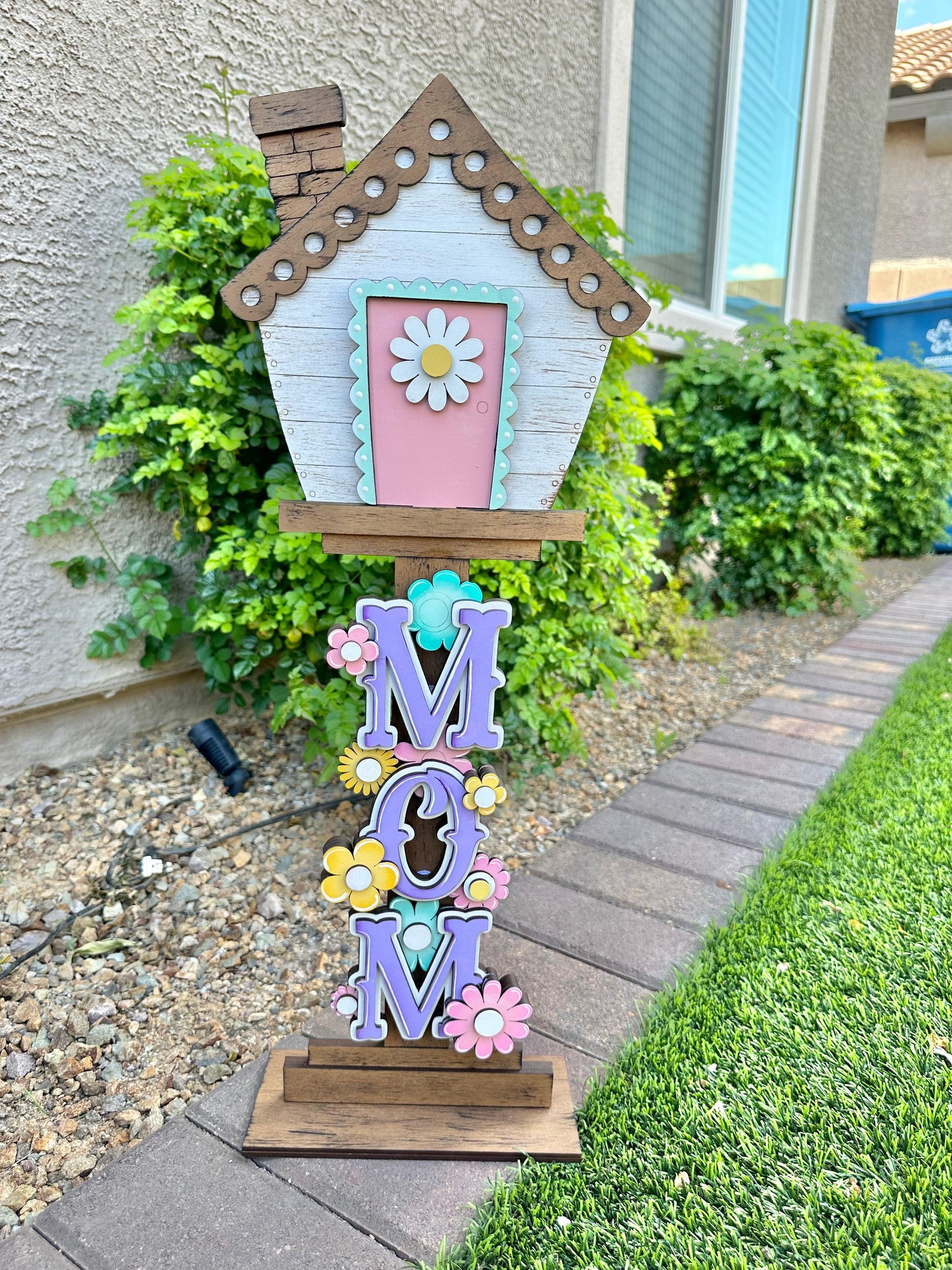 a colorful birdhouse with a flowered roof on a lawn